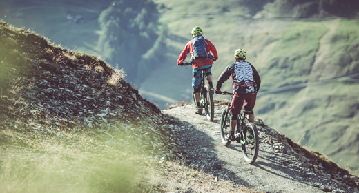 Bikers su sentiero che conduce verso l'Alpe Mine a Livigno dal Mottolino Bikepark con MTB